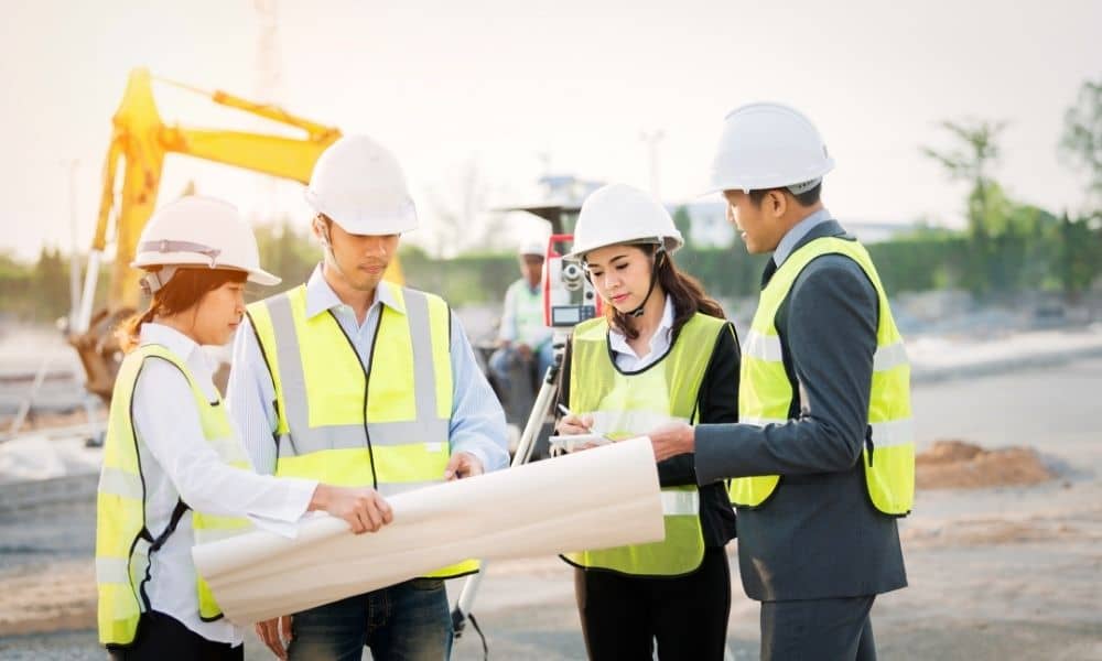 Land survey team reviewing site plans and taking measurements for a property development project