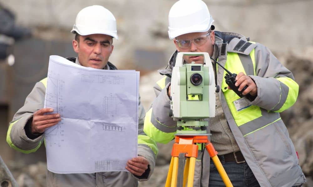 Surveyors review a plan beside a total station during ALTA survey fieldwork