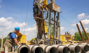 Construction staking geothermal borehole drilling - ALTA SURVEY Connecticut Geothermal drilling rig and worker on a construction site where construction staking guides borehole placement