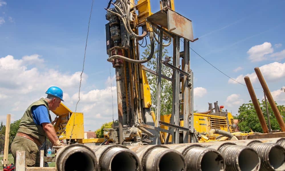 Construction staking geothermal borehole drilling - ALTA SURVEY Connecticut Geothermal drilling rig and worker on a construction site where construction staking guides borehole placement